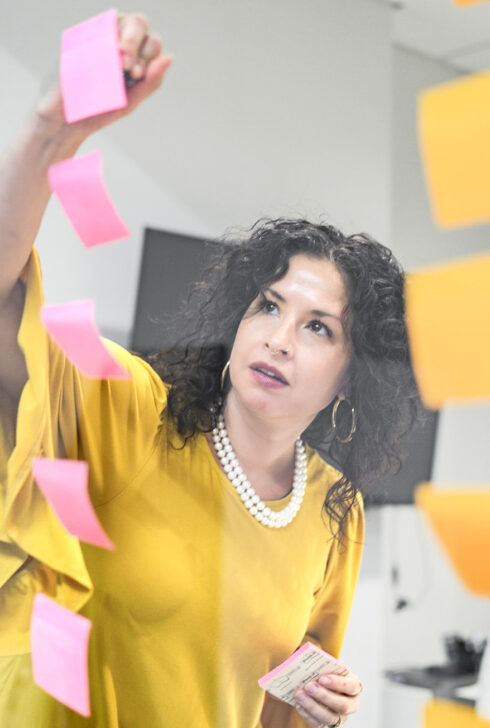 Jen Rittenhouse notating a post-it note in a strategy session in a conference room.