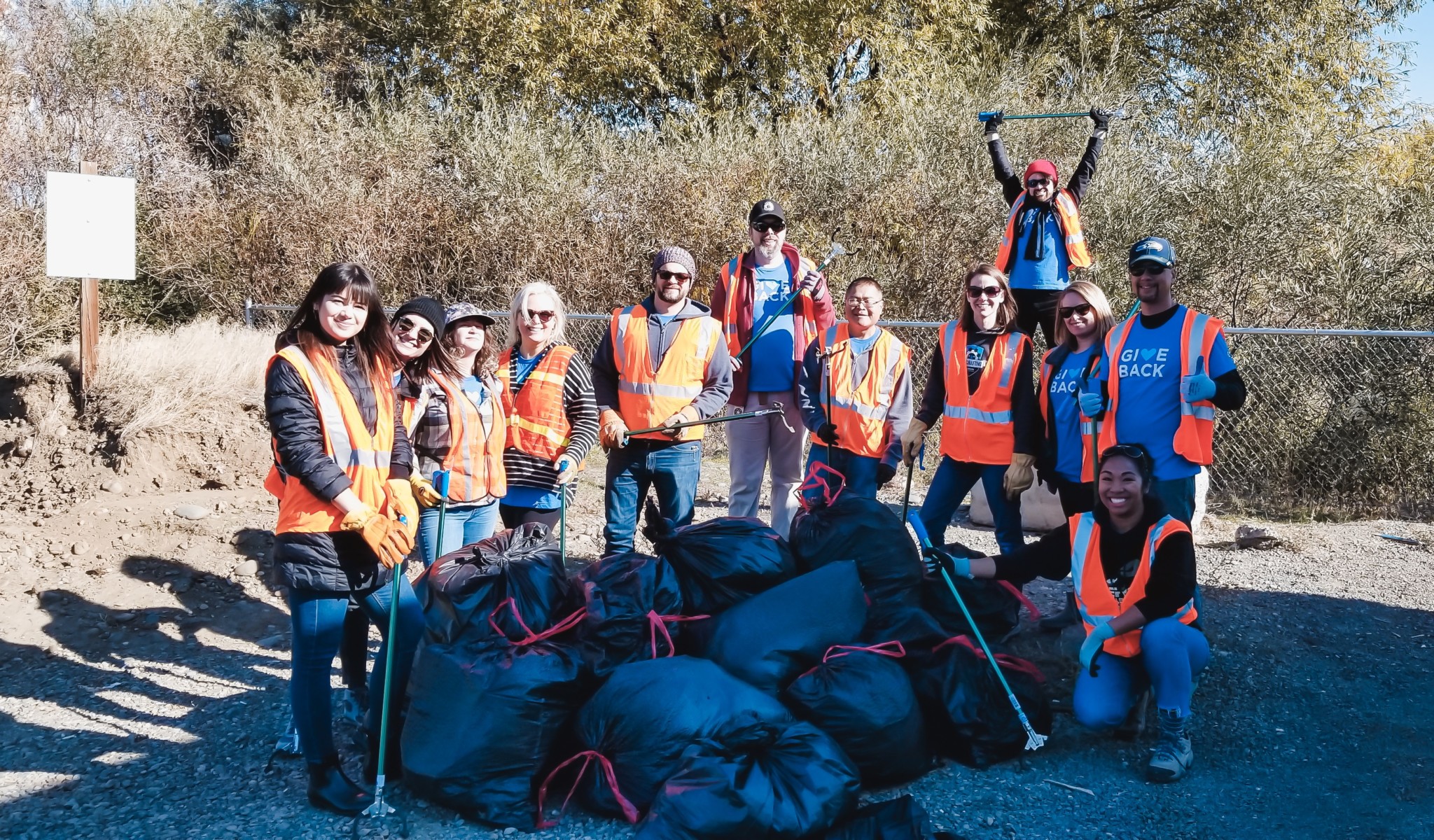 SiteCrafting team members wearing blue give back t-shirts and orange reflective vests volunteering to clean up trash along a highway in Ellensburg Washington.