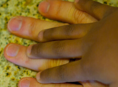 African American child's hand on a Caucasian mans hand.