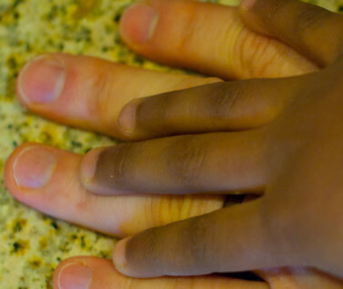 African American child's hand on a Caucasian mans hand.