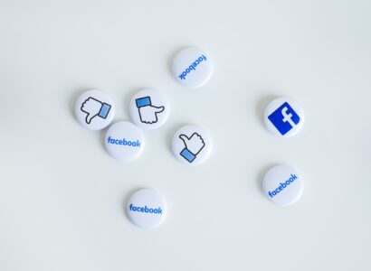 Facebook logo pins and thumbs up pins on a white counter.