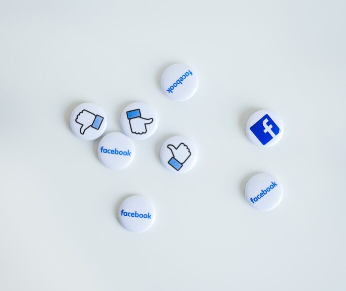 Facebook logo pins and thumbs up pins on a white counter.