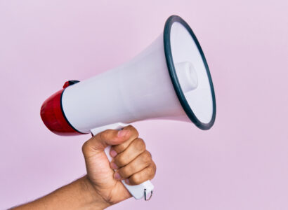 Hand holding a megaphone on a pink background