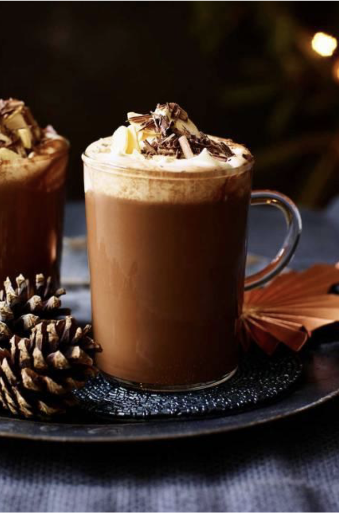 Glass mug of hot chocolate with whip cream and chocolate sprinkles