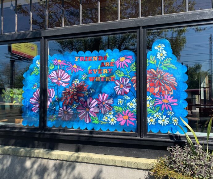 Store window painted with flowers and the phrase Friends are everywhere