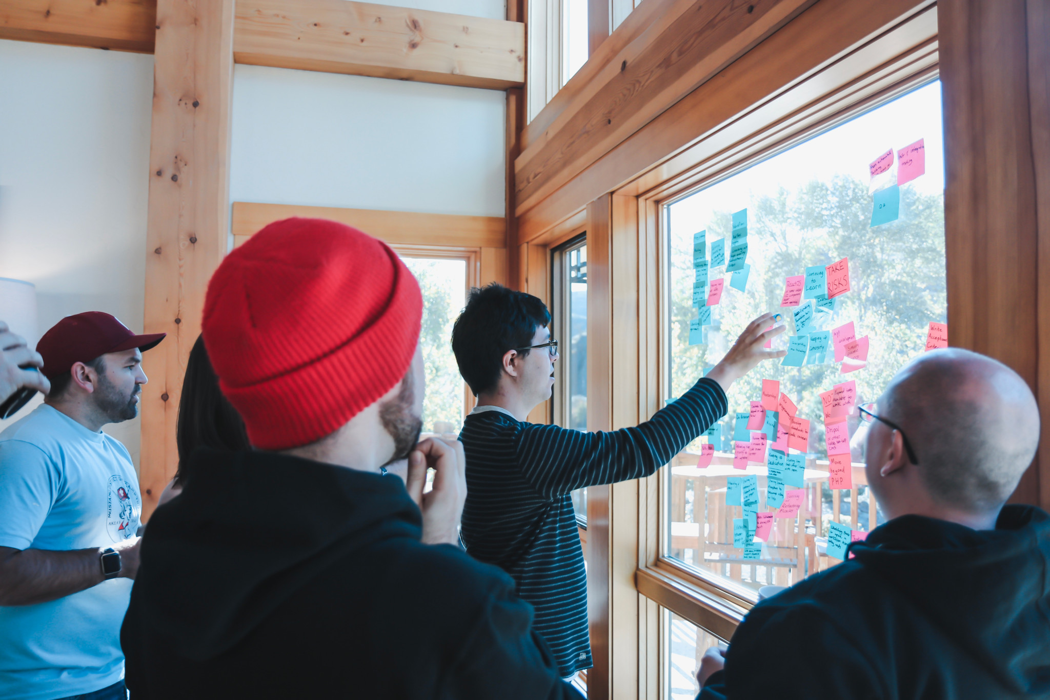 A group of people studying post-it notes on a window.