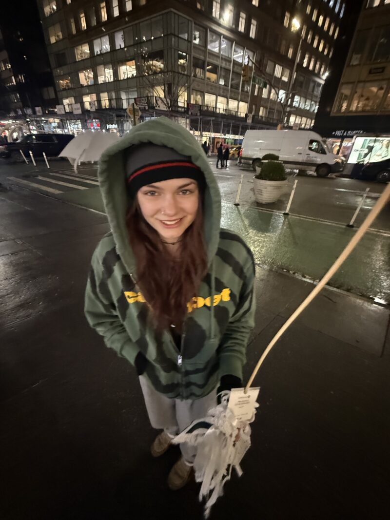 Employee Charlotte posing on the sidewalk with buildings lit up at night
