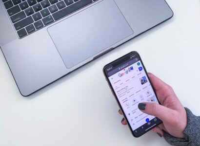 Woman's hand holding a mobile phone with google search results showing SiteCrafting business information.
