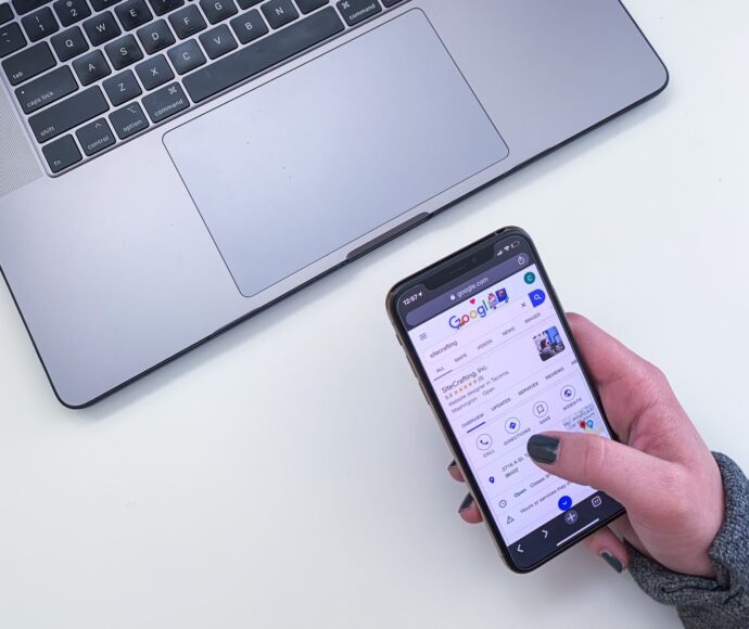 Woman's hand holding a mobile phone with google search results showing SiteCrafting business information.
