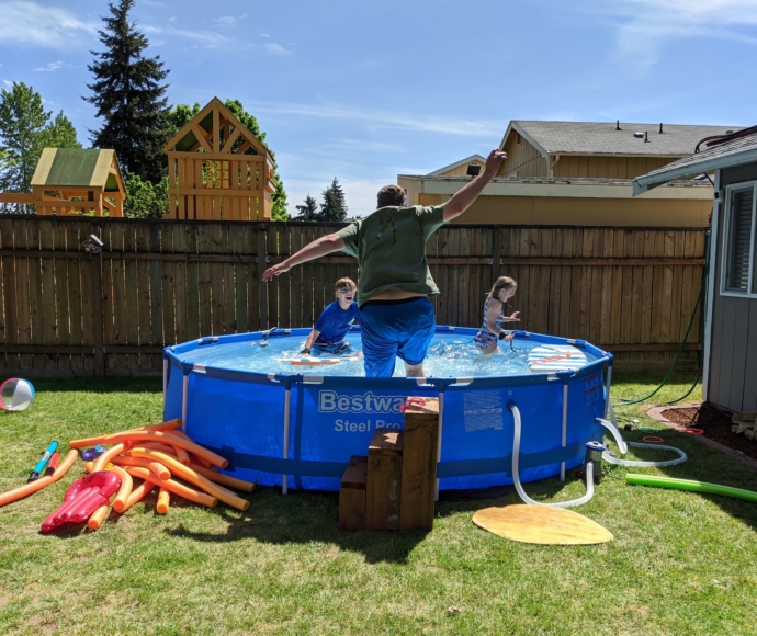 Mark Neidlinger jumping into a swimming pool with his kids.