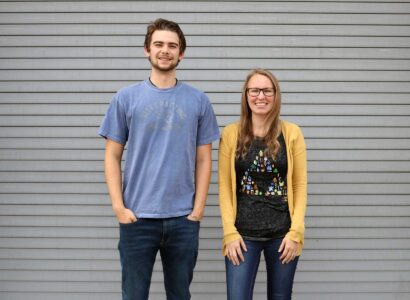 SiteCrafting interns Nick and Leah standing in front of a gray wall.