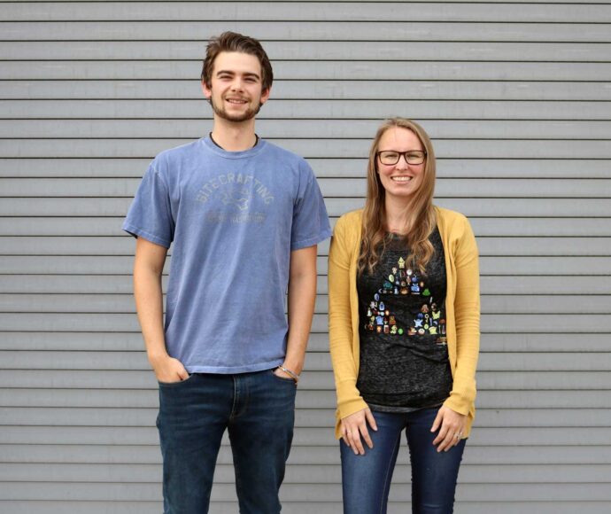 SiteCrafting interns Nick and Leah standing in front of a gray wall.