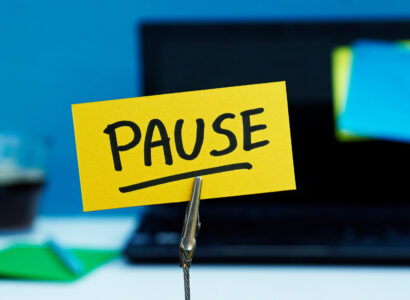 Pause written on yellow post-it, in front of an open laptop