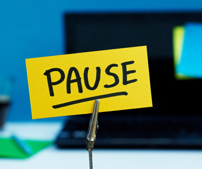 Pause written on yellow post-it, in front of an open laptop