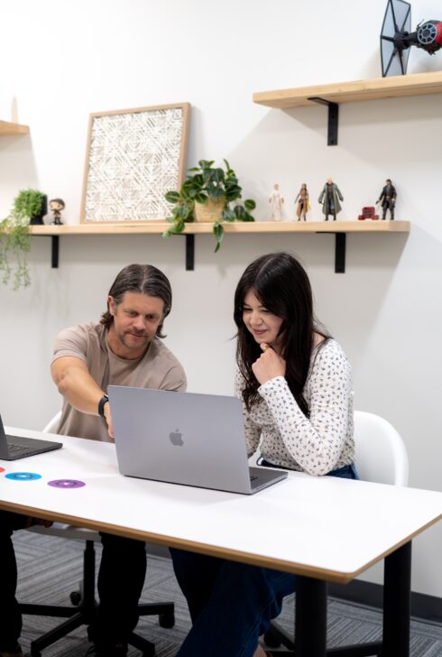 SiteCrafting employees sitting in a conference room pointing to a laptop.