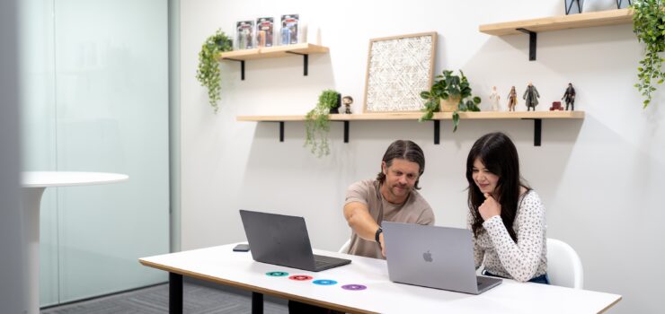SiteCrafting employees sitting in a conference room pointing to a laptop.