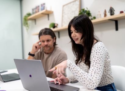 Employee pointing to laptop screen with fellow employee looking over