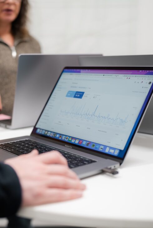 Laptop screen with people gathered around it.