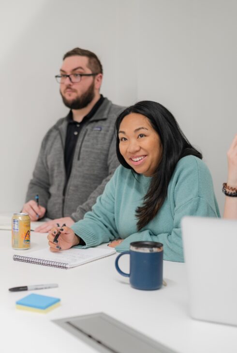 Employee smiling while taking notes in a meeting.