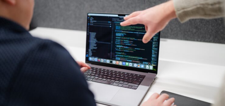Employees discussing code on a laptop.