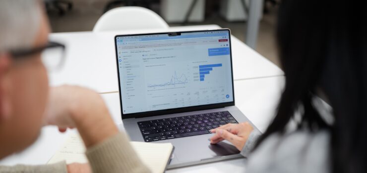 Two employees looking at a laptop with analytics on the screen.