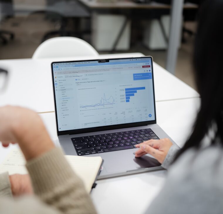 Two employees looking at a laptop with analytics on the screen.
