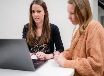 Reena Hensley and Leah Ruisenor collaborating at a laptop.