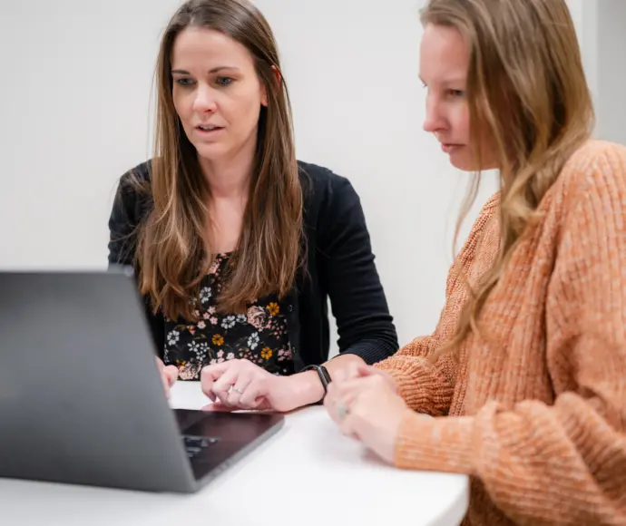 Reena Hensley and Leah Ruisenor collaborating at a laptop.