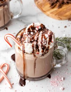 Glass mug of hot chocolate with chocolate drizzle and a candy cane