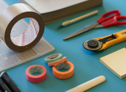 Various tools, tape and paper on a desk.