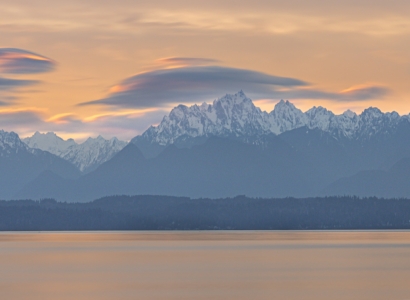 Mountain range seen from across a bay of water during dusk.