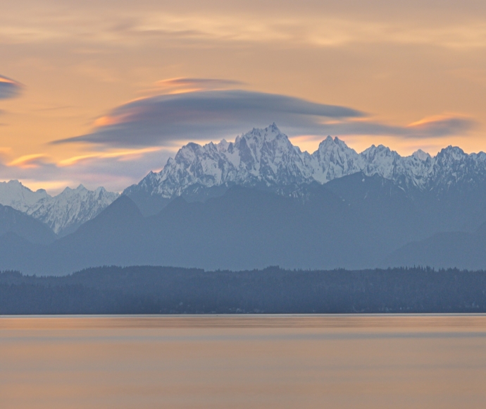 Mountain range seen from across a bay of water during dusk.