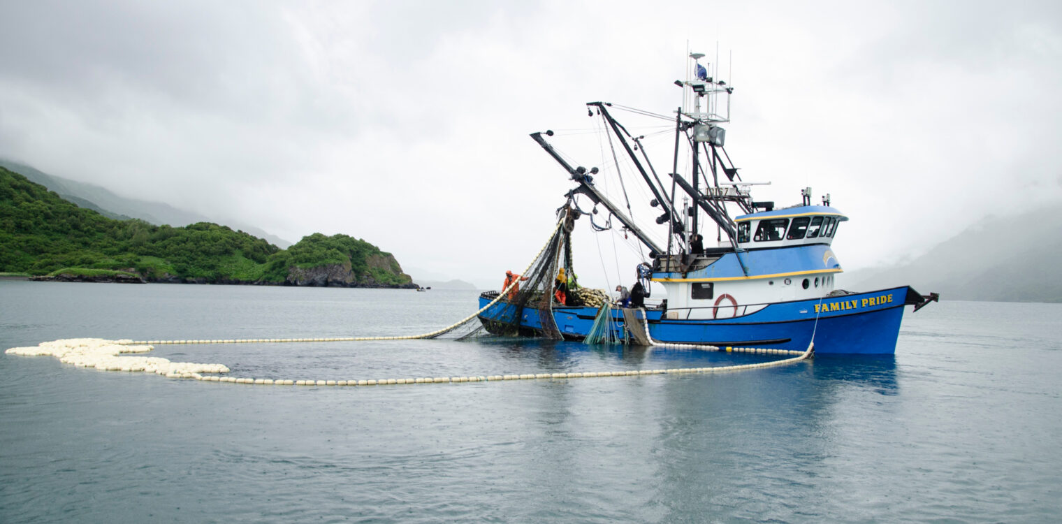 Blue fishing boat titled Family Pride shown in the water with nets out.