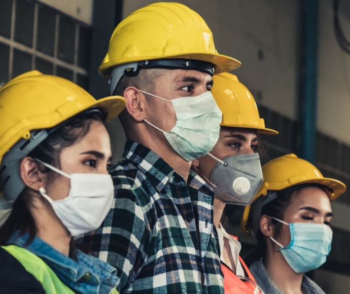 Group of people wearing hard hats and masks.