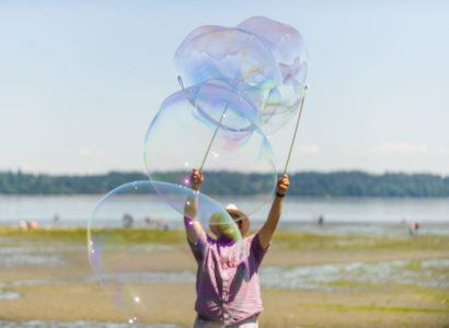 Man at the beach blowing monster bubbles.