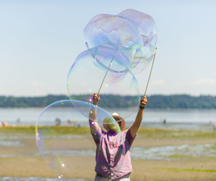Man at the beach blowing monster bubbles.