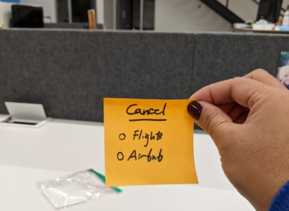 Woman holding post-it note that reads cancel flights and airbnb