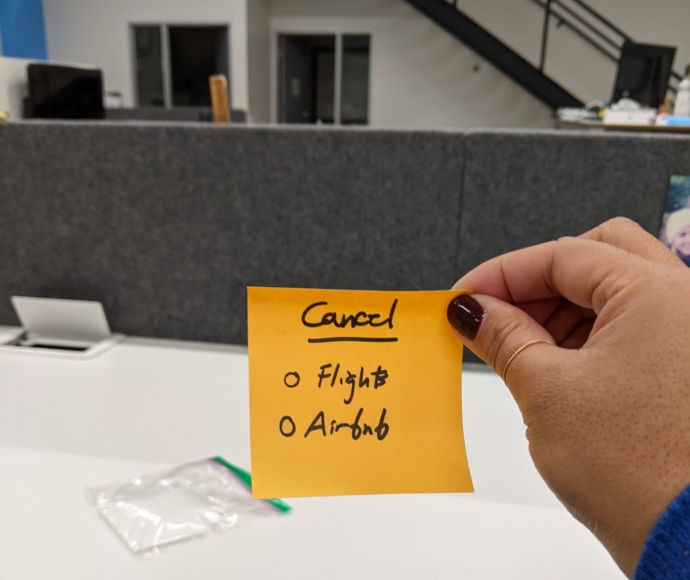 Woman holding post-it note that reads cancel flights and airbnb
