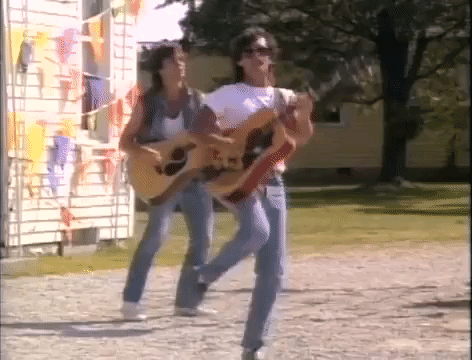 John Mellencamp dancing and playing the guitar.
