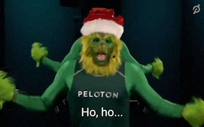 A man dressed as the Grinch with painted green skin and a Peloton tank top saying "Ho, ho, no!"