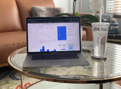 Laptop showing with the google analytics dashboard open while sitting on a coffee table next to a glass of water.