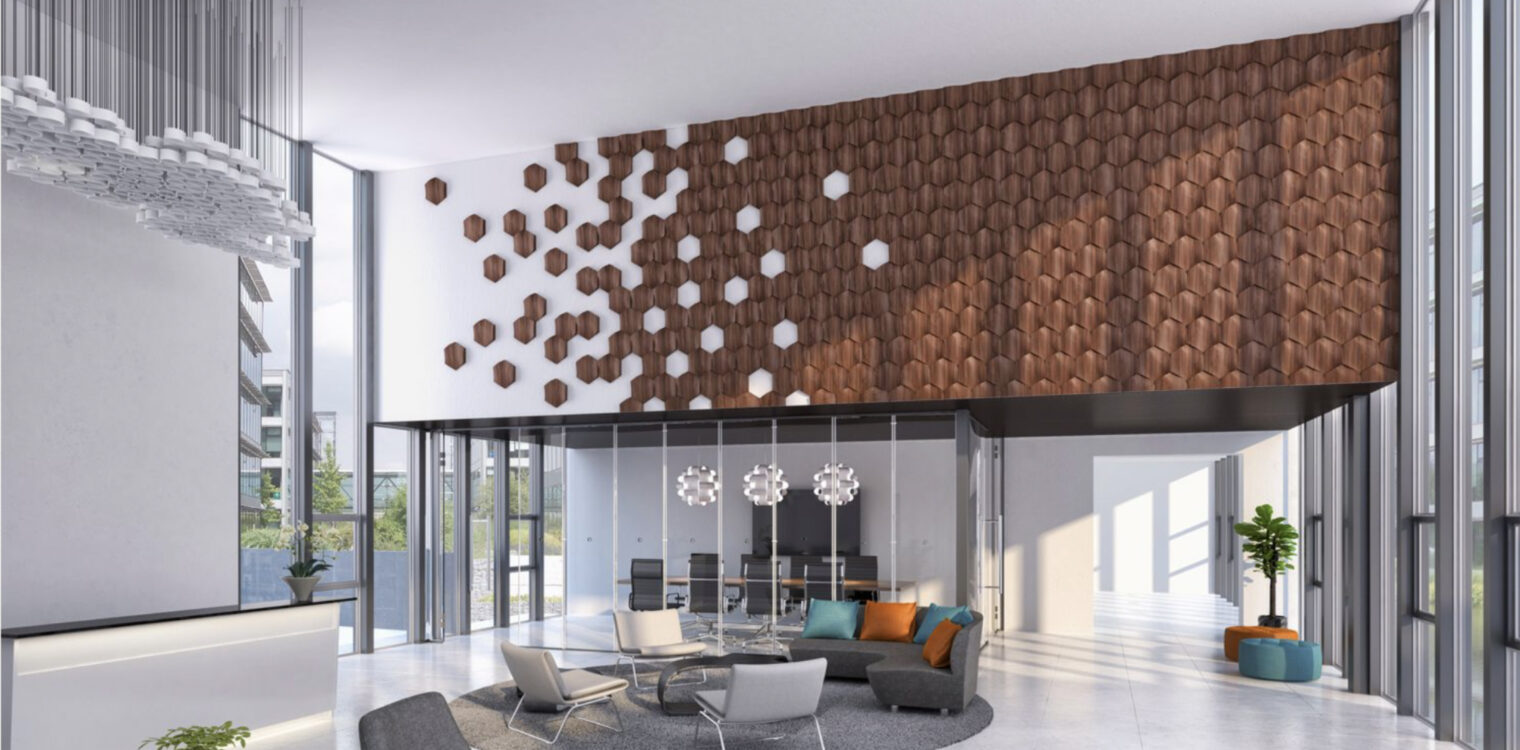 Contemporary lobby with hexagonal wooden wall panels, a reception desk with a plant, a sculptural chandelier, and a central seating area featuring chairs, a sofa, and a round coffee table. A glass partition reveals a conference room in the background, with natural light streaming through large windows.