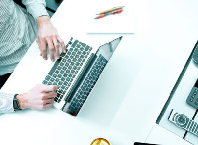 Person sitting at a desk typing on a laptop.