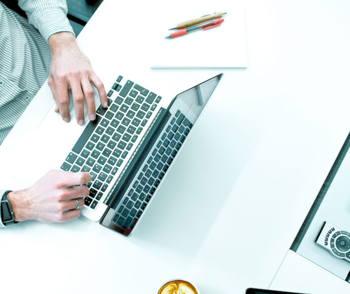 Person sitting at a desk typing on a laptop.