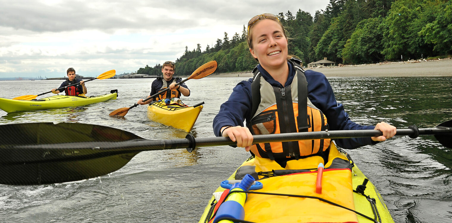 Three people kayaking in the pacific northwest.