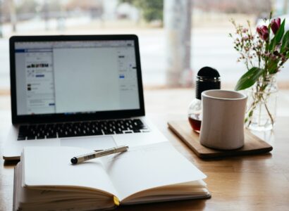 Blank notebook on a desk in front of an open laptop