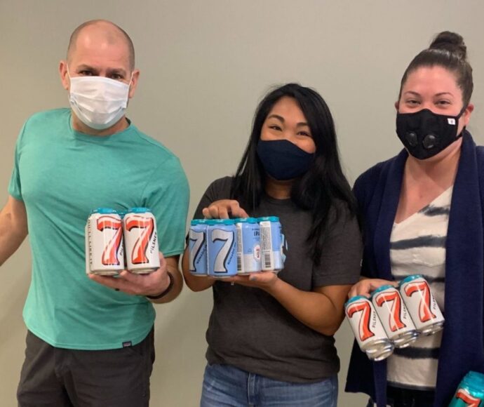 Brian Forth, Angie Carson and Michelle Harrison holding cans of 7 Seas Brewery cans of beer.