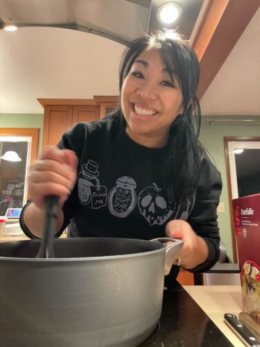 Angie smiling while cooking a meal on the stove