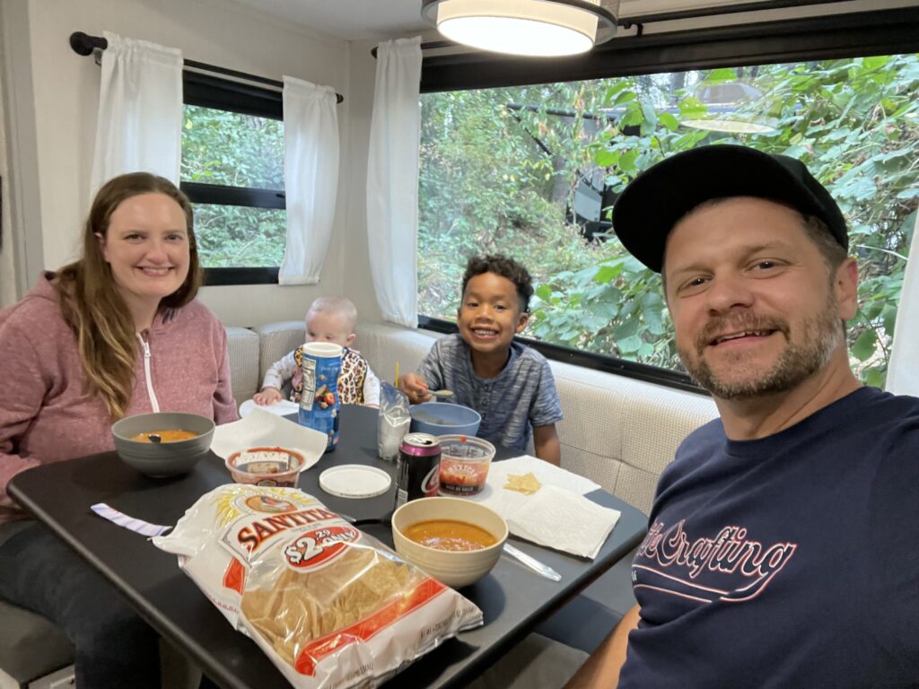 Aaron Marth, his wife, and two kids eating a meal together inside their RV