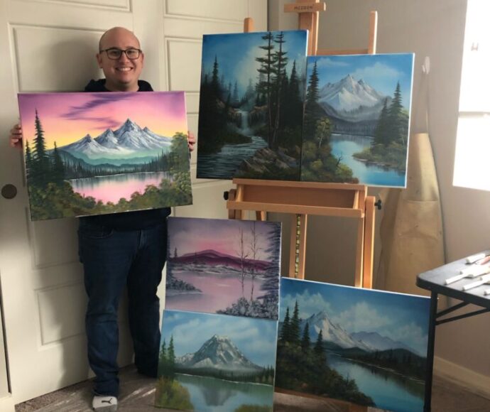 Daniel showing off five of his paintings inspired by Bob Ross